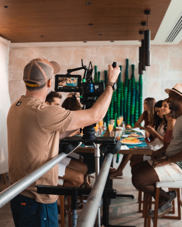 Video production crew filming people dining at a resort restaurant