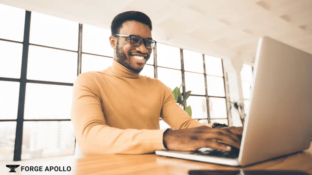 Man smiling while using a laptop for email marketing