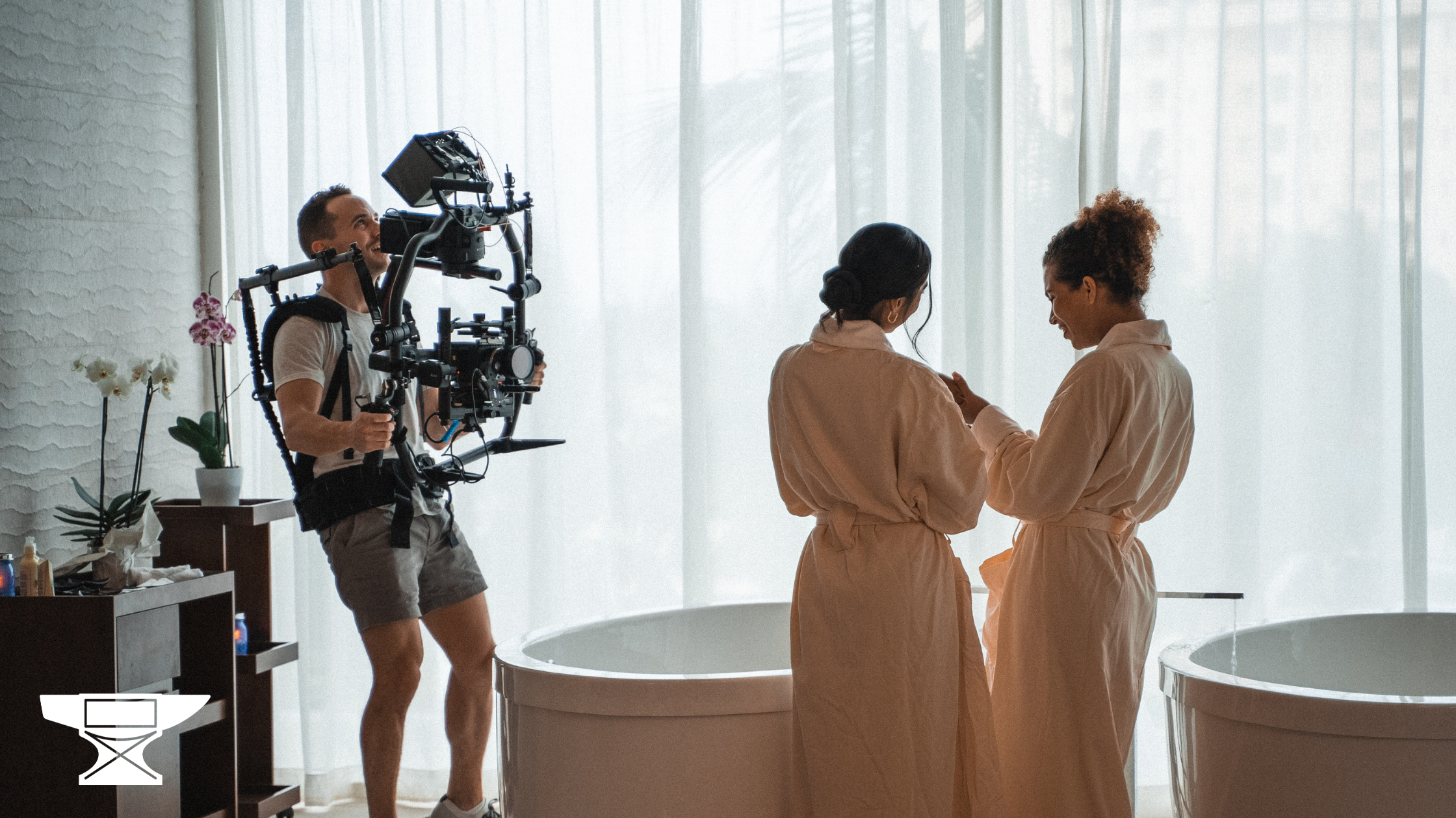 Video production crew member filming two women talking in a resort spa
