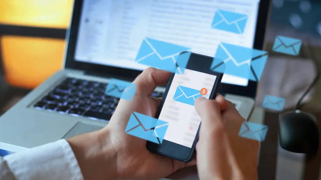 Hands holding a phone with email icons surrounding it