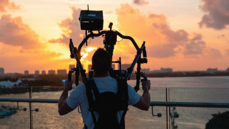 Person using video production equipment to film a sunset over a city skyline