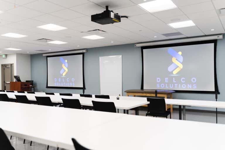 Classroom with Delco Solutions' logo on the drop down screens