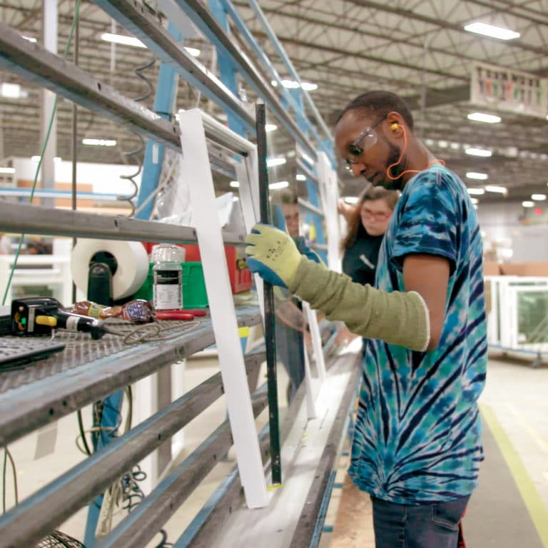 Castle Windows employee inserting glass into a window frame