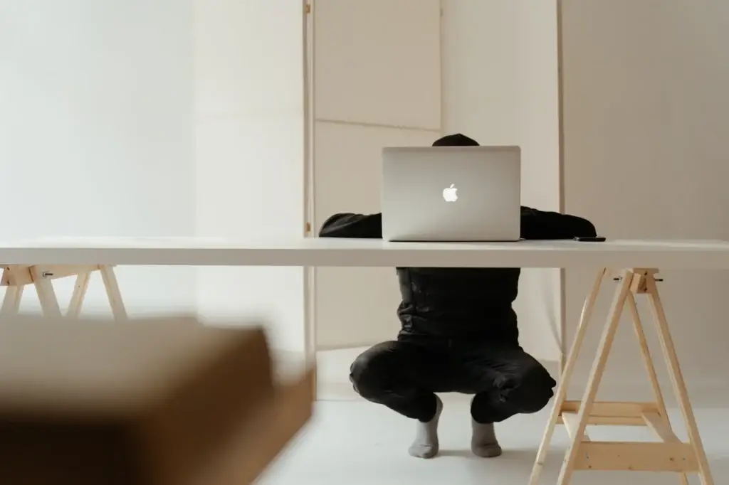 Person crouched at a table using their laptop