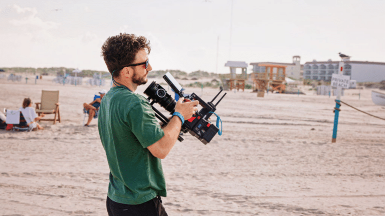 Travel video producer holding a camera on the beach
