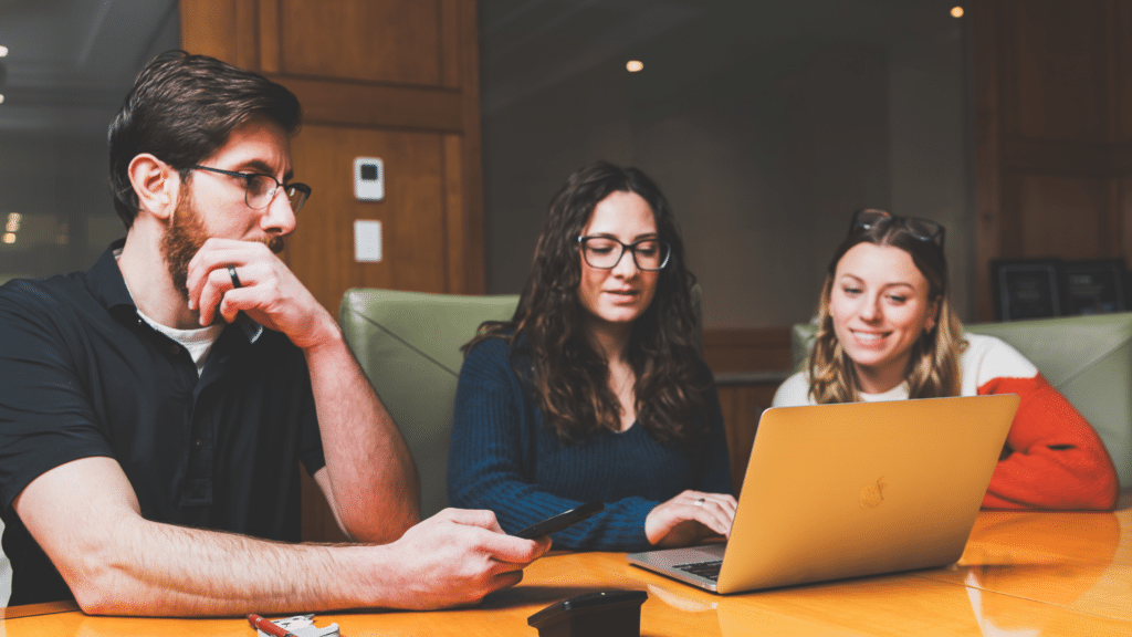 Three people looking at a website on a laptop