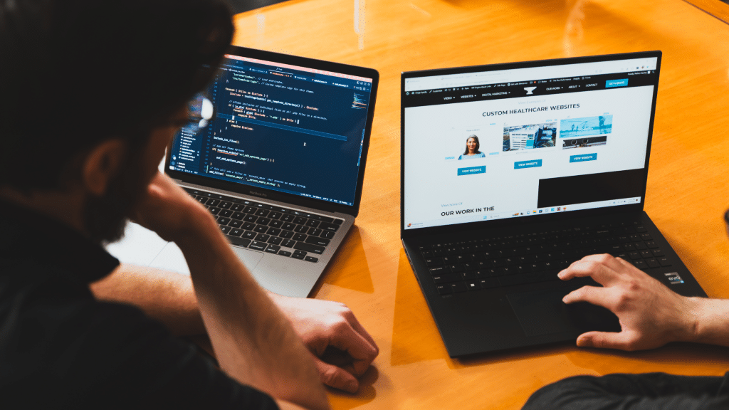 Two laptops side by side, one showing the website code and the other showing the website design.