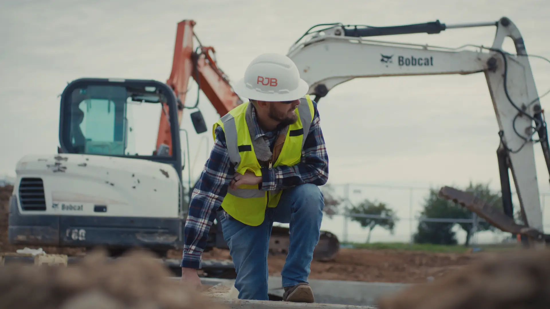 B2B contractor posing in front of an excavator