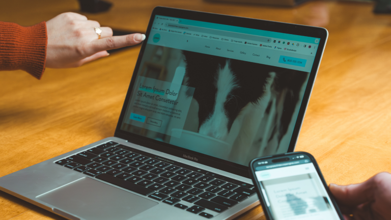 Designer reviewing a website design on a laptop and mobile view